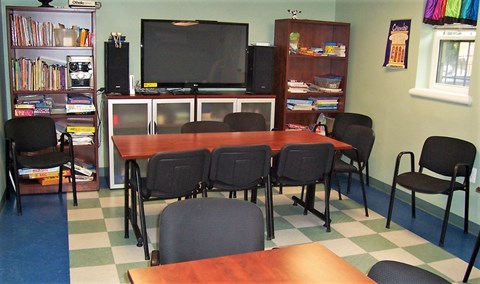 a conference room with a table and chairs and a television